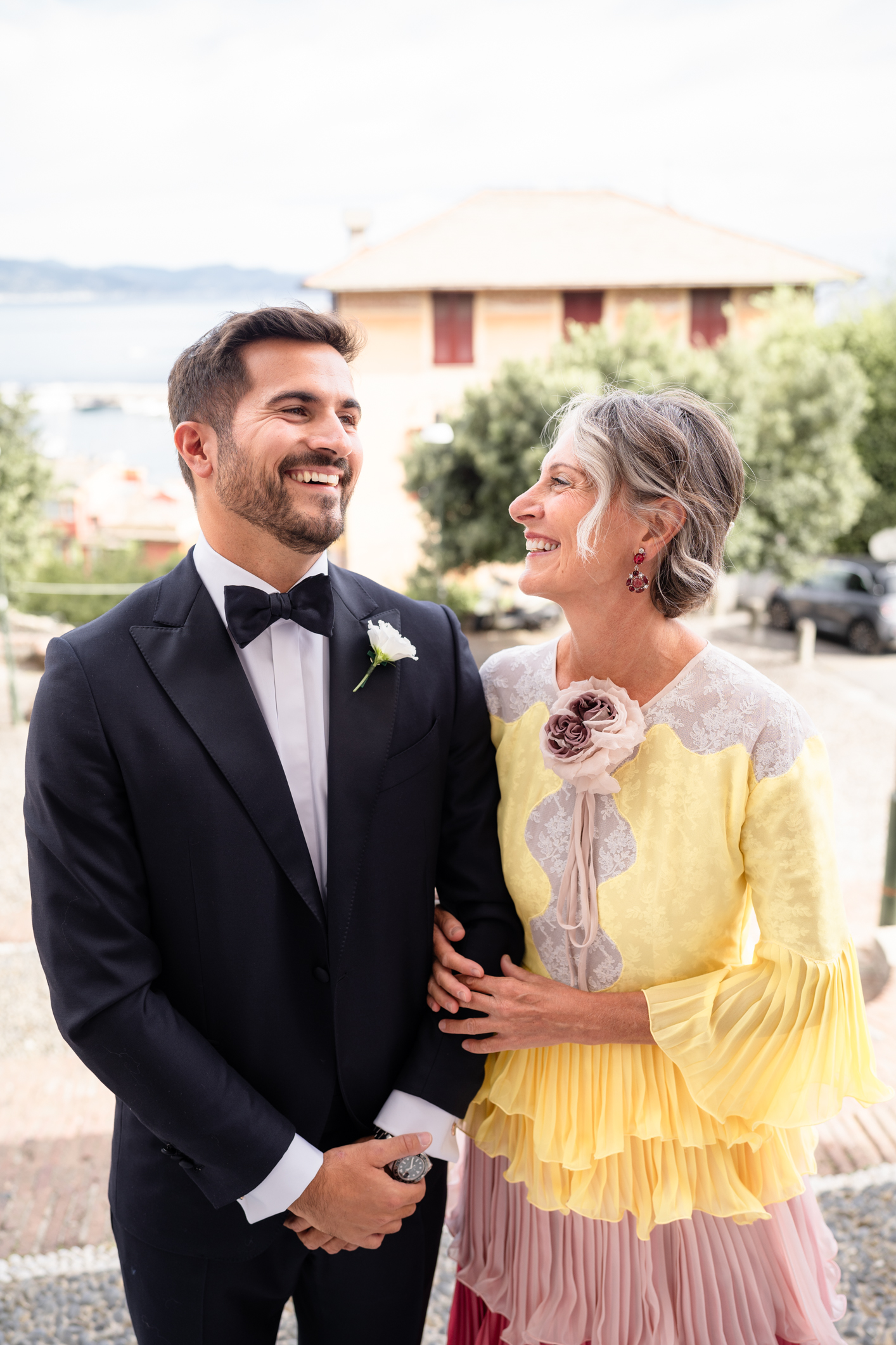 Elegant wedding in Portofino, with a view of the Ligurian bay, celebration at the historic Vesta Portofino by Dolce & Gabbana venue, capturing the atmosphere of the Dolce Vita and the Italian Riviera, bride with bouquet going to the cerimony in Portofino, groom with mum in font of the church