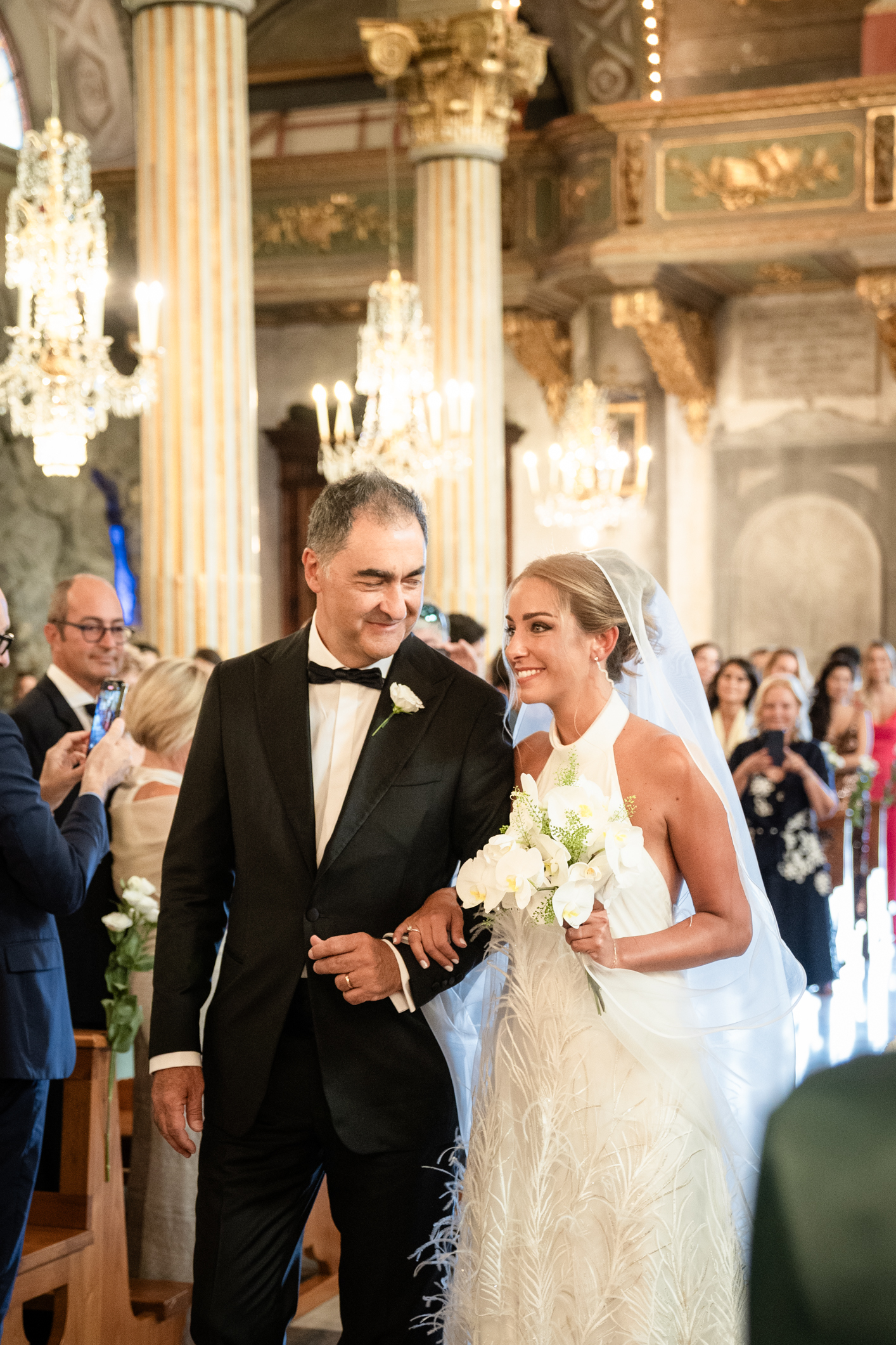 Elegant wedding in Portofino, with a view of the Ligurian bay, celebration at the historic Vesta Portofino by Dolce & Gabbana venue, capturing the atmosphere of the Dolce Vita and the Italian Riviera, bride with bouquet going to the cerimony with dad