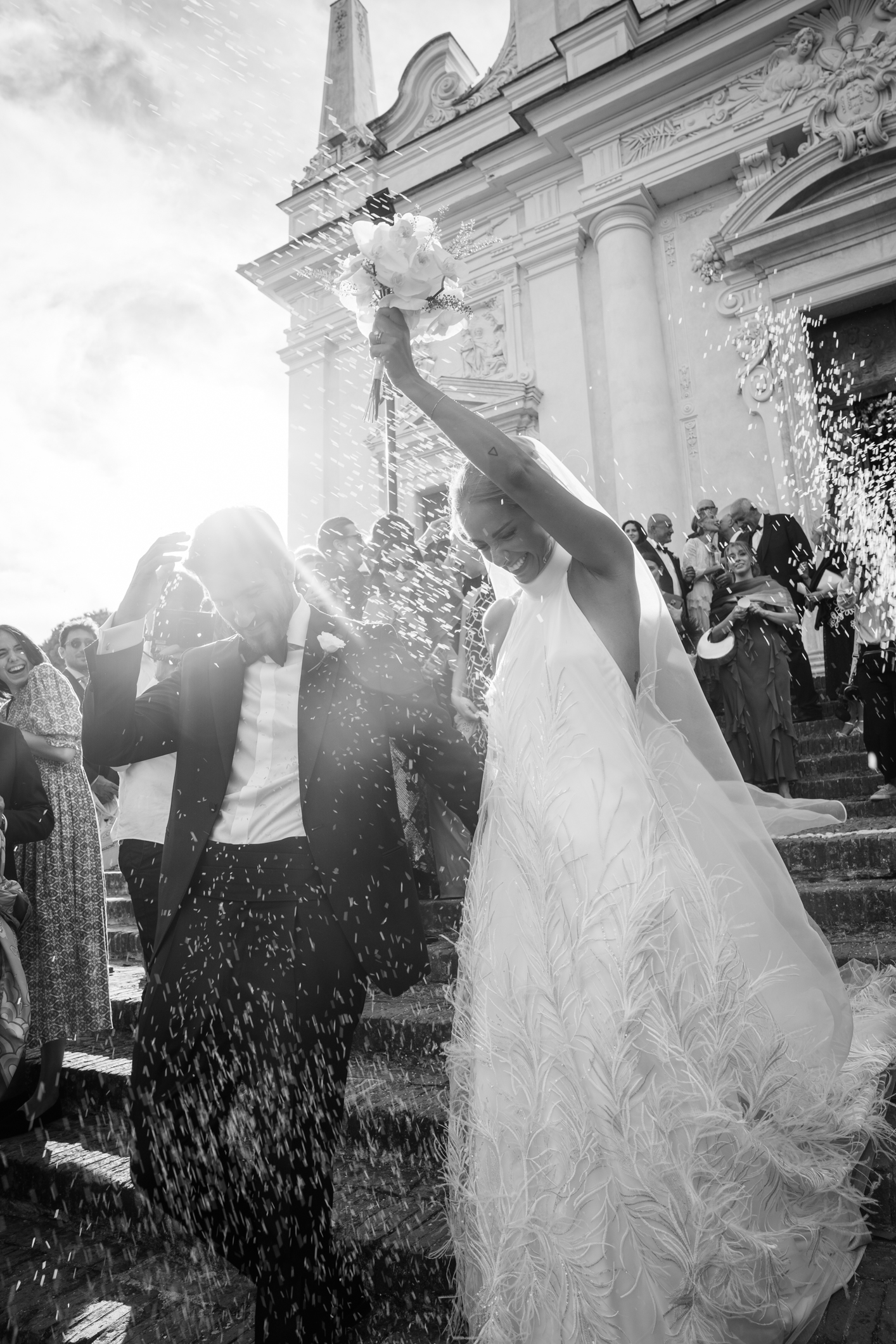 Elegant wedding in Portofino, with a view of the Ligurian bay, celebration at the historic Vesta Portofino by Dolce & Gabbana venue, capturing the atmosphere of the Dolce Vita and the Italian Riviera, bride and groom outside the church during the traditional rice toss